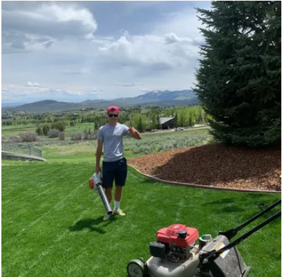 Lawn care worker using a blower beside maintained turf